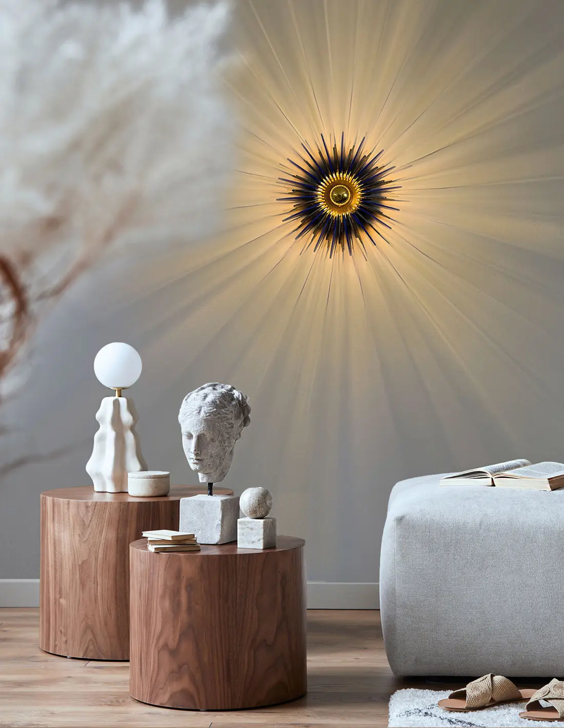 Moderne Wandlampe strahlt Lichtstrahlen über stilvolle Inneneinrichtung aus, mit Skulpturen und Designer-Möbeln auf Holztischen.